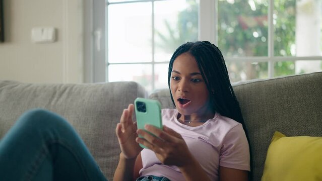 African american woman using smartphone with cheerful expression at home
