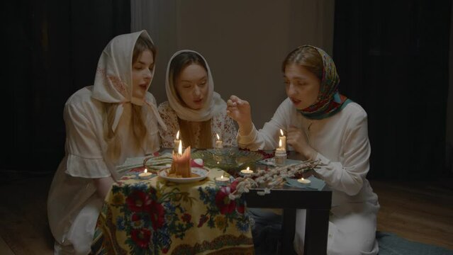 4K. Slavic women are guessing with a ring in a dark room by candlelight