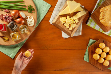 Woman´s hand holding brazilian cheese stuffed croquette (bolinha de queijo) on a wooden table. Top view.