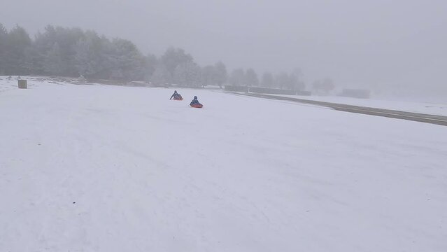 Two kids racing with sleds and one of them ends up capsizing