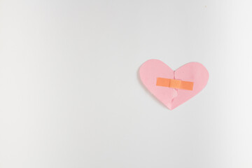 Broken pink heart with band-aid