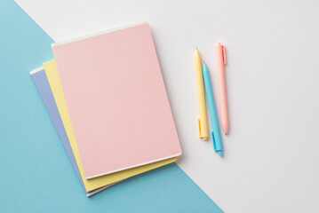 Back to school concept. Top view photo of colorful diaries and pens on bicolor blue and white background