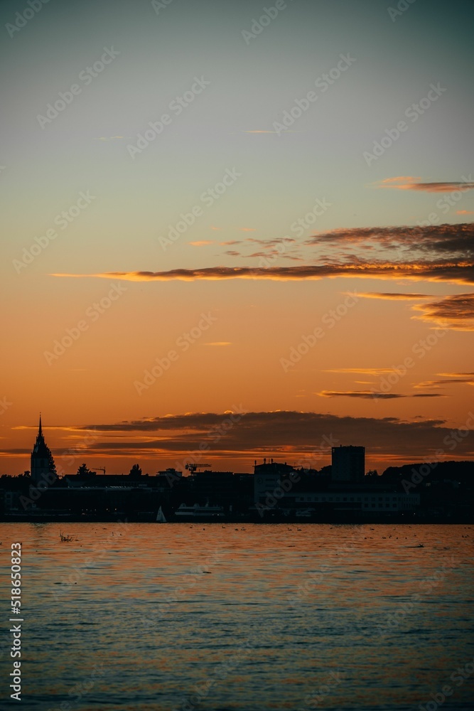 Canvas Prints Vertical shot of bright sunset sky over the lake the backdrop of the urban landscape on summer day