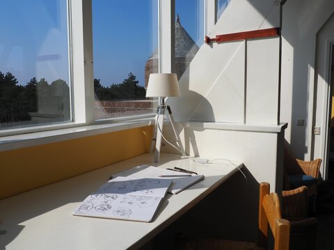 Cozy corner in the room with sketchnotes, pens and a lamp on the table