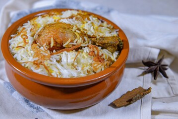 Chicken biriyani with raita and pickle served in a golden dish isolated on dark background side view
