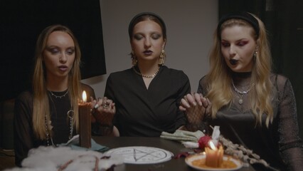 4K. Three female witches in a dark room conduct mystical sessions