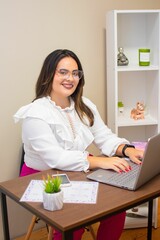 Vertical view of a happy female working in the office with her laptop