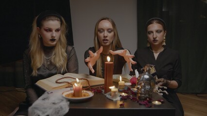4K. Three female witches in a dark room conduct mystical sessions