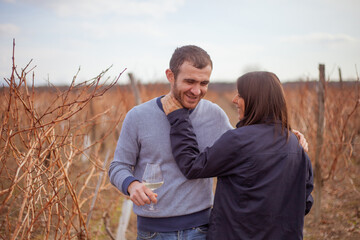 couple man and woman in the middle of a vineyard in autumn with glasses of white wine