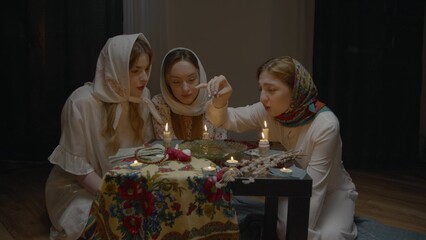 4K. Slavic women are guessing with a ring in a dark room by candlelight