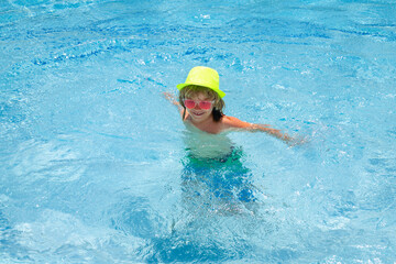 Fototapeta na wymiar Kid boy playing in swimming pool. Fashion summer kids in hat and pink sunglasses. Child splashing in swimming pool.