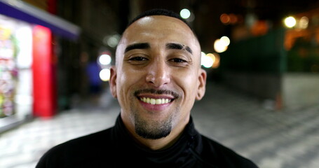 Brazilian hispanic man smiling at camera in city at night - Powered by Adobe