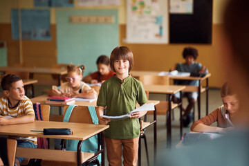 Happy kid reading his assignment during class at school.