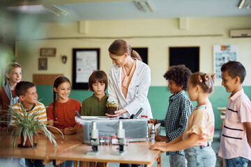 Happy teacher and school kids having botany class at school.