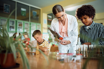 School kids having class with science teacher in classroom.