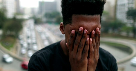 Anxious young black African man suffering in city