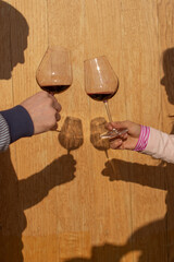 couple stand with glasses of wine opposite each other on a wooden background with beautiful shadows