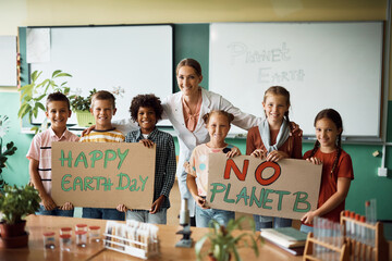 Happy science teacher and school children who are holding placard with 'Happy Earth day' and 'No...