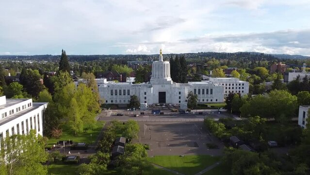 Aerial drone footage of the white building of the Oregon State Capitol with a green park in Salem