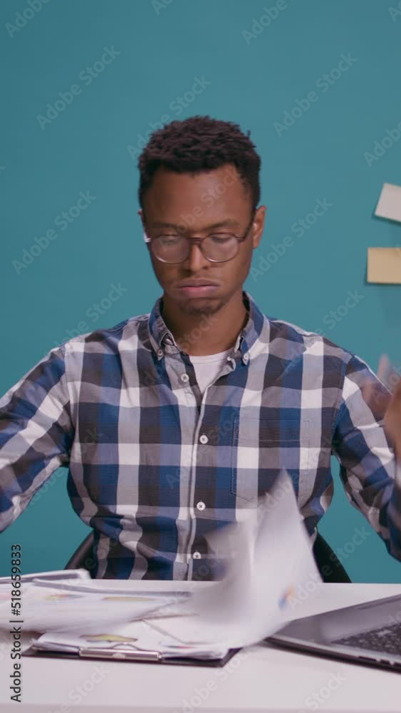 Poster vertical video: young business man sorting out financial charts on papers, analyzing documents to cr
