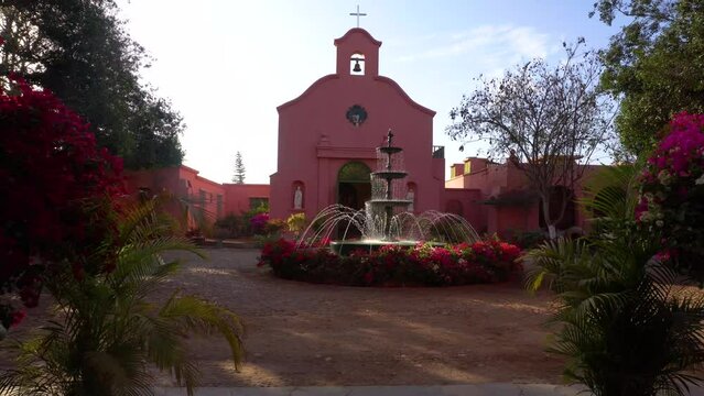 Old church with a fountain adorned with flowers on a sunny day in Hacienda Bodega Tacama