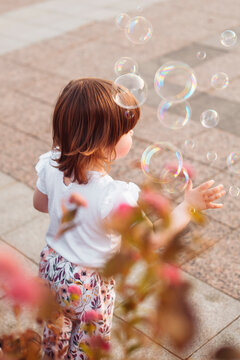 little girl playing on the street with blowing soap bubbles