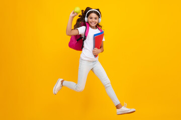 Fototapeta na wymiar Schoolchild, teenage student girl with headphones and school bag backpack on yellow isolated studio background. Children school and education concept.