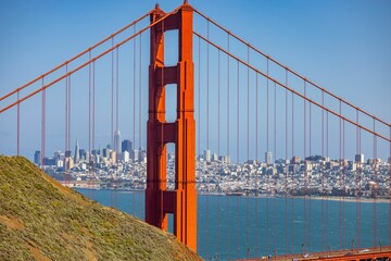 Scenic view of the famous Golden gate bridge against the cityscape on a sunny day - obrazy, fototapety, plakaty