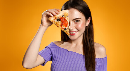 Beautiful girl showing slice of pizza near her face and smiling, recommending take out food,...