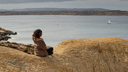 Girl sitting on the top of cliff in Malta, Selmun