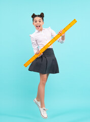 Amazed teenager. Back to school. School girl hold ruler measuring isolated on blue background. Excited teen schoolgirl.