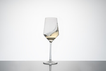 white wine movement inside a crystal glass. white wine glass on white background with reflection on the base. image for cutout.