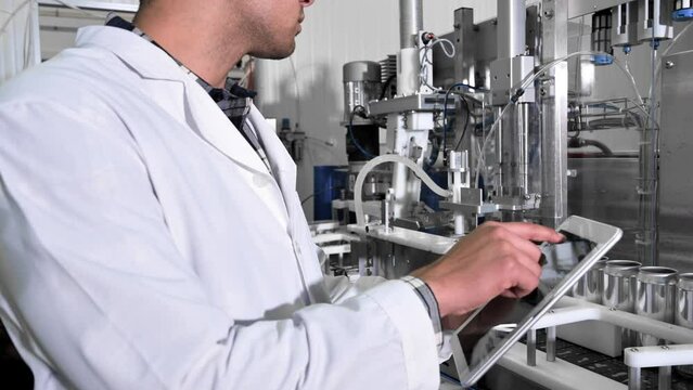 Factory worker inspecting production line on beverage factory with computer tablet. High quality 4k footage