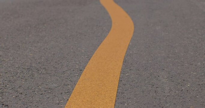 Orange line on the asphalt road. Curved drawing of markings on the road, traffic control. Offset markings on a hot day, melted paint.