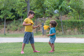 Fototapeta premium Dreams of flying. Happy childhood concept. Two boy play with a toy plane at sunset. Children on background of sun with an airplane in hand. Silhouette of children playing on the plane