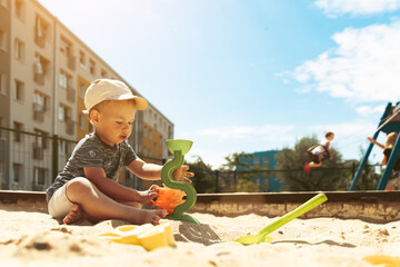 Child playing in sandbox. Little boy having fun on playground in sandpit. Outdoor creative activities for kids. Summer and childhood concept