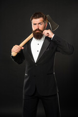Serious bearded man twirling mustache while carrying axe at dark background, barber