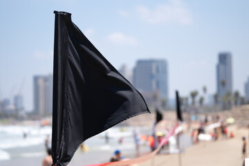 Black flag on the sea shore warning about dangerous current and waves or invasion of jellyfish.