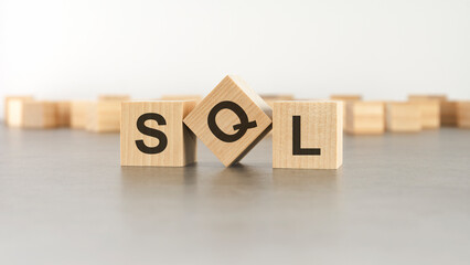 wooden cube with the letter from the SQL word. wooden cubes standing on gray background. SQL - short for Structured Query Language