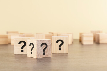 cube with question mark on wooden background. space for text