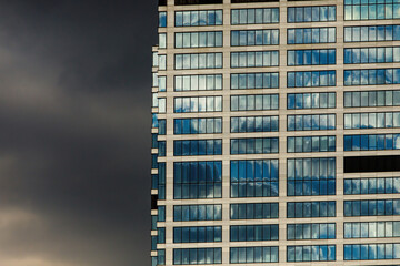 Mirrored office building windows with dramatic clouds background.