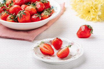 Ripe juicy strawberries in plates on a white tablecloth on the table