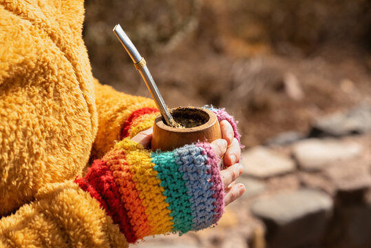 SOSTENIENDO UN MATE CON LAS MANOS ENGUANTADAS. FOTO HORIZONTAL. COLOR.	