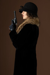 A 1920s woman wearing a black velvet coat with a fur collar and holding a gun