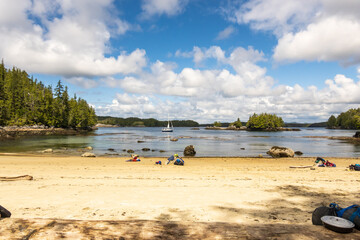 Remote wilderness beach and sea with white clouds and blue sky sailboat at anchor