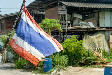 The national flag of Thailand flutters on the street on the outskirts of the city.