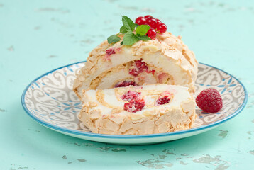 Baked meringue roll with red berries on a round plate, white background