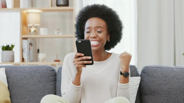Shocked woman shouting and cheering with joy while reading an email with good news on the couch at home. Surprised and cheerful black female excited after getting back test results or winning a game
