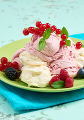 Vanilla and raspberry ice cream scoops on a round green plate