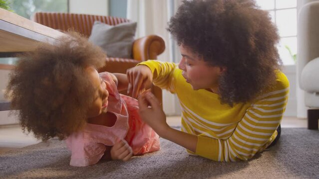 Mother tickling laughing daughter having fun playing game lying on floor at home - shot in slow motion